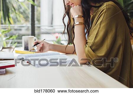 Stock Image - Caucasian woman studying at desk. Fotosearch