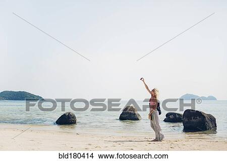 Picture - Caucasian woman taking selfie on beach. Fotosearch