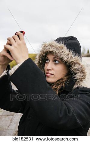 Stock Image - Caucasian woman taking selfie outdoors. Fotosearch
