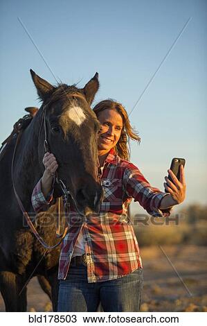 Stock Image - Caucasian woman taking selfie with horse. Fotosearch