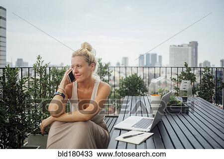 Caucasian woman talking on cell phone on balcony View Large Photo Image Stock Image - Caucasian woman talking on cell phone on balcony. Fotosearch
