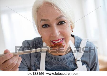 Stock Photograph - Caucasian woman tasting sauce. Fotosearch