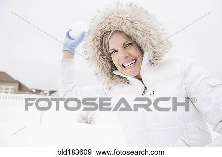 Stock Photo - Caucasian woman throwing snowball in snow. Fotosearch