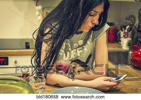 Caucasian woman using cell phone in kitchen View Large Photo Image Stock Photo - Caucasian woman using cell phone in kitchen. Fotosearch