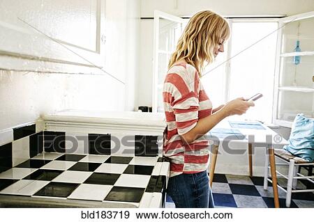 Caucasian woman using cell phone in kitchen View Large Photo Image Stock Photo - Caucasian woman using cell phone in kitchen. Fotosearch