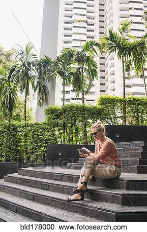 Caucasian woman using cell phone on stairs View Large Photo Image Stock Image - Caucasian woman using cell phone on stairs. Fotosearch