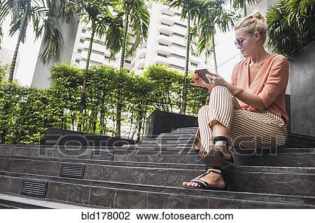 Caucasian woman using cell phone on stairs View Large Photo Image Stock Image - Caucasian woman using cell phone on stairs. Fotosearch