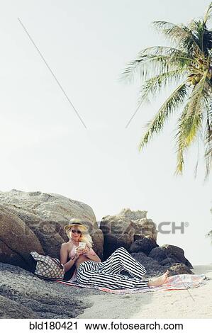 Stock Image - Caucasian woman using cell phone on beach. Fotosearch
