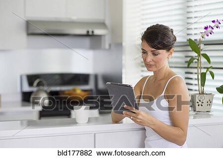 Caucasian woman using digital tablet in kitchen View Large Photo Image Stock Image - Caucasian woman using digital tablet in kitchen. Fotosearch