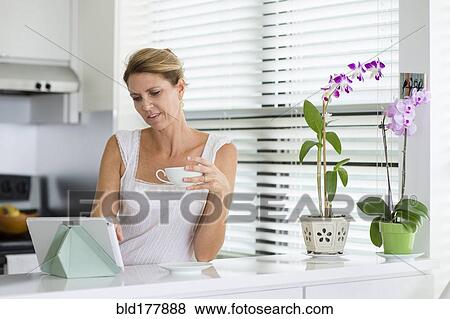 Caucasian woman using digital tablet in kitchen View Large Photo Image Stock Photo - Caucasian woman using digital tablet in kitchen. Fotosearch