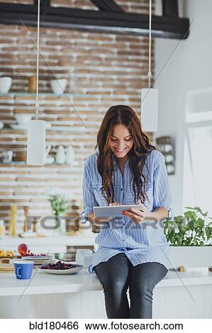 Caucasian woman using digital tablet in kitchen View Large Photo Image Stock Photograph - Caucasian woman using digital tablet in kitchen. Fotosearch