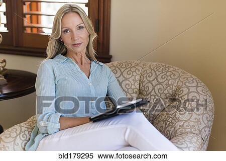 Stock Photography - Caucasian woman using digital tablet in armchair. Fotosearch