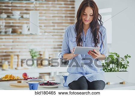 Caucasian woman using digital tablet in kitchen View Large Photo Image Stock Photography - Caucasian woman using digital tablet in kitchen. Fotosearch