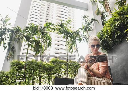Stock Image - Caucasian woman using digital tablet on stairs. Fotosearch