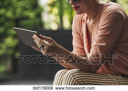 Stock Photo - Caucasian woman using digital tablet outdoors. Fotosearch