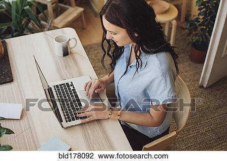 Stock Image - Caucasian woman using laptop at desk. Fotosearch