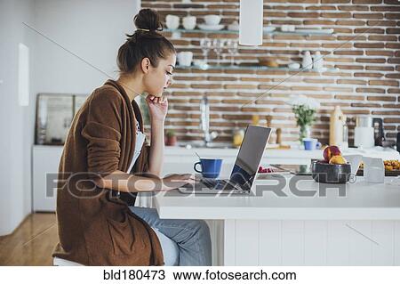 Caucasian woman using laptop in kitchen View Large Photo Image Stock Image - Caucasian woman using laptop in kitchen. Fotosearch