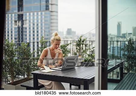 Stock Photography - Caucasian woman using laptop on balcony. Fotosearch