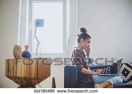 Stock Photo - Caucasian woman using laptop on sofa. Fotosearch