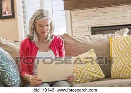 Caucasian woman using laptop on sofa View Large Photo Image Stock Photograph - Caucasian woman using laptop on sofa. Fotosearch