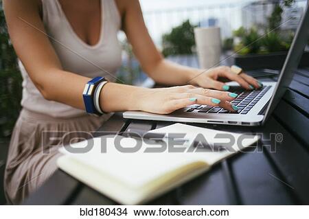 Picture - Caucasian woman using laptop outdoors. Fotosearch