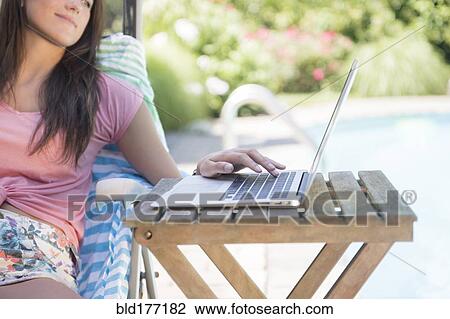 Stock Image - Caucasian woman using laptop outdoors. Fotosearch