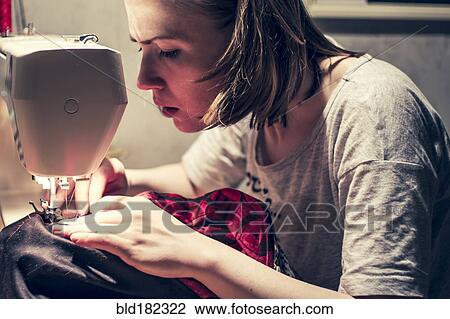 Stock Image - Caucasian woman using sewing machine. Fotosearch