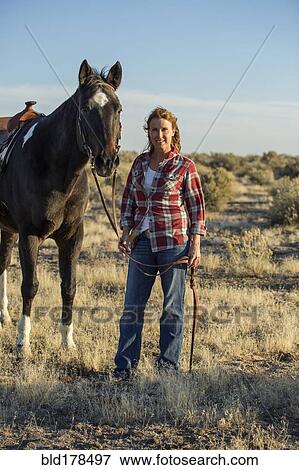 Stock Photo - Caucasian woman walking horse in field. Fotosearch