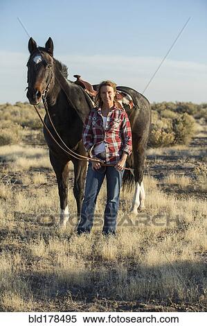 Stock Photography - Caucasian woman walking horse in field. Fotosearch
