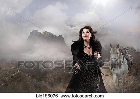 Stock Photograph - Caucasian woman walking horse in remote landscape. Fotosearch
