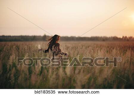 Caucasian woman walking in rural field View Large Photo Image Stock Photography - Caucasian woman walking in rural field. Fotosearch