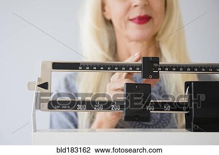 Caucasian woman weighing herself on scale View Large Photo Image Stock Image - Caucasian woman weighing herself on scale. Fotosearch