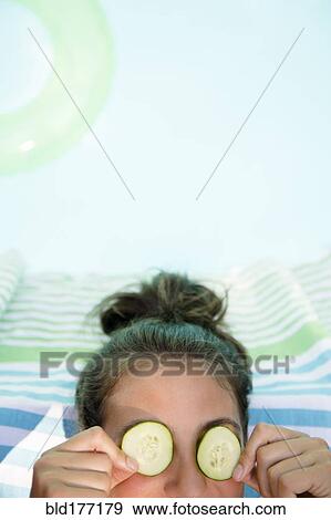 Stock Photo - Caucasian woman with cucumbers on eyes. Fotosearch