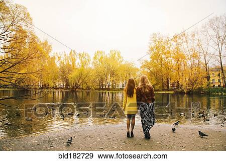 Stock Photo - Caucasian women admiring pond in park. Fotosearch
