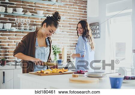 Stock Image - Caucasian women chopping fruit in kitchen. Fotosearch