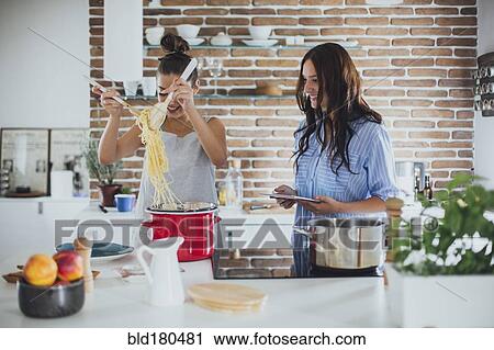 Stock Image - Caucasian women cooking pasta in kitchen. Fotosearch