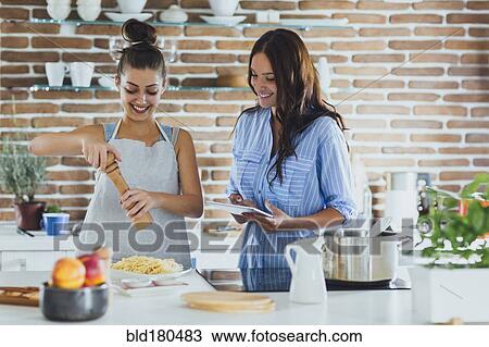 Stock Image - Caucasian women cooking pasta in kitchen. Fotosearch