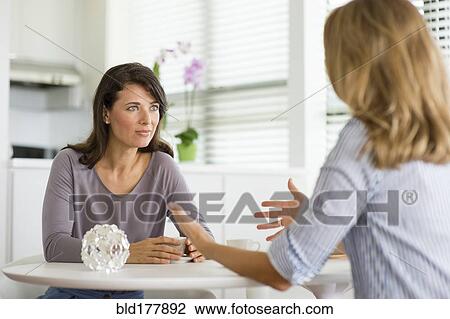 Stock Image - Caucasian women drinking coffee in kitchen. Fotosearch