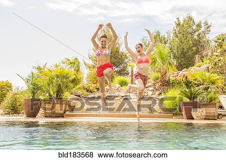 Stock Photo - Caucasian women jumping into swimming pool. Fotosearch