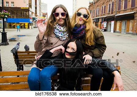 Stock Photo - Caucasian women posing on bench. Fotosearch