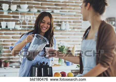 Caucasian women pouring smoothie in kitchen View Large Photo Image Stock Photograph - Caucasian women pouring smoothie in kitchen. Fotosearch