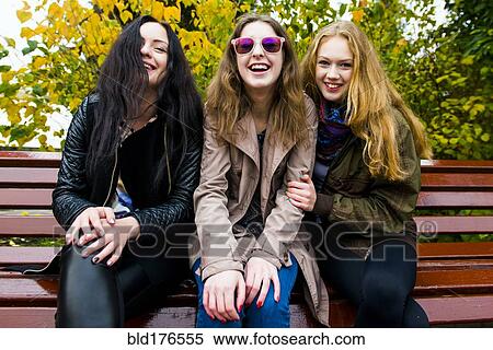 Stock Photography - Caucasian women smiling on bench. Fotosearch