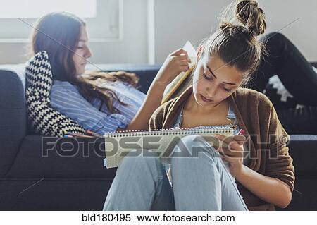 Stock Photography - Caucasian women studying in living room. Fotosearch