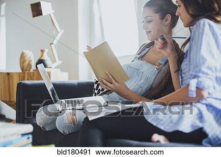 Stock Image - Caucasian women studying on sofa. Fotosearch