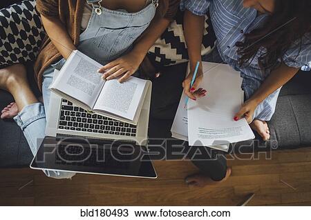Stock Image - Caucasian women studying on sofa. Fotosearch