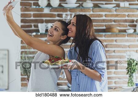 Caucasian women taking selfie in kitchen with pasta View Large Photo Image Stock Photo - Caucasian women taking selfie in kitchen with pasta. Fotosearch