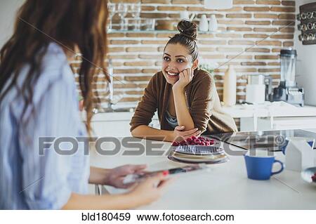 Stock Photo - Caucasian women talking in kitchen. Fotosearch