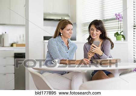 Caucasian women using cell phone in kitchen View Large Photo Image Stock Photography - Caucasian women using cell phone in kitchen. Fotosearch