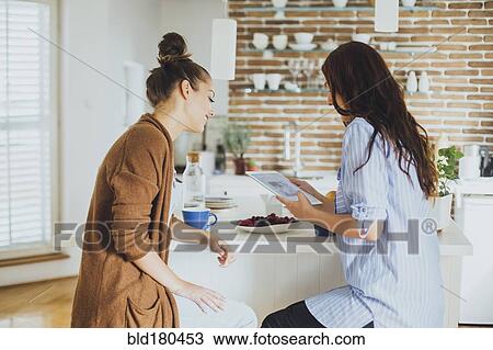 Stock Image - Caucasian women using digital tablet at counter. Fotosearch