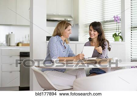 Picture - Caucasian women using digital tablet in kitchen. Fotosearch